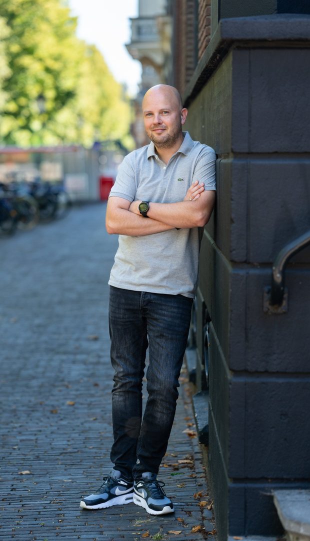 Erwin Kampen, leunend tegen een gevel in een straat met klinkers